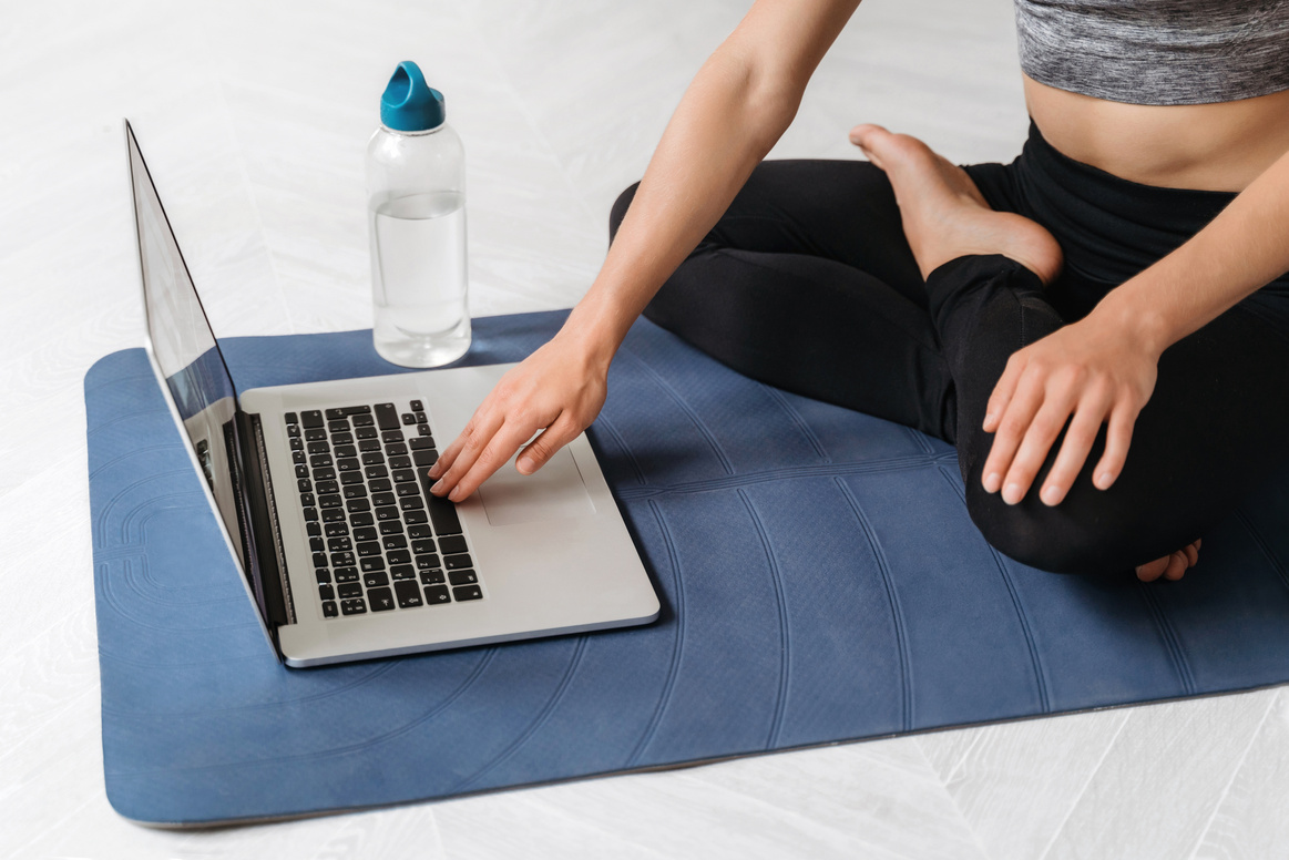 Fit woman practicing yoga online with laptop